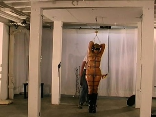 Undressed babe stands with her significant boobs tied up in ropes