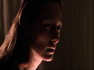 Tilda Swinton leaning over a bowl of water to splash her