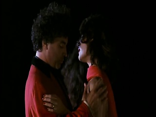 Claudia Koll standing outside as a guy pulls her white