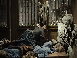 Doutzen Kroes lying on her back on a bed wearing corset and