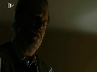 Noomi Rapace lying on her stomach on a bed, her hands and