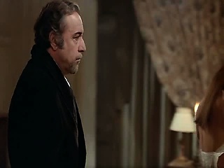 Carole Bouquet standing in front of a mirror as she undoes